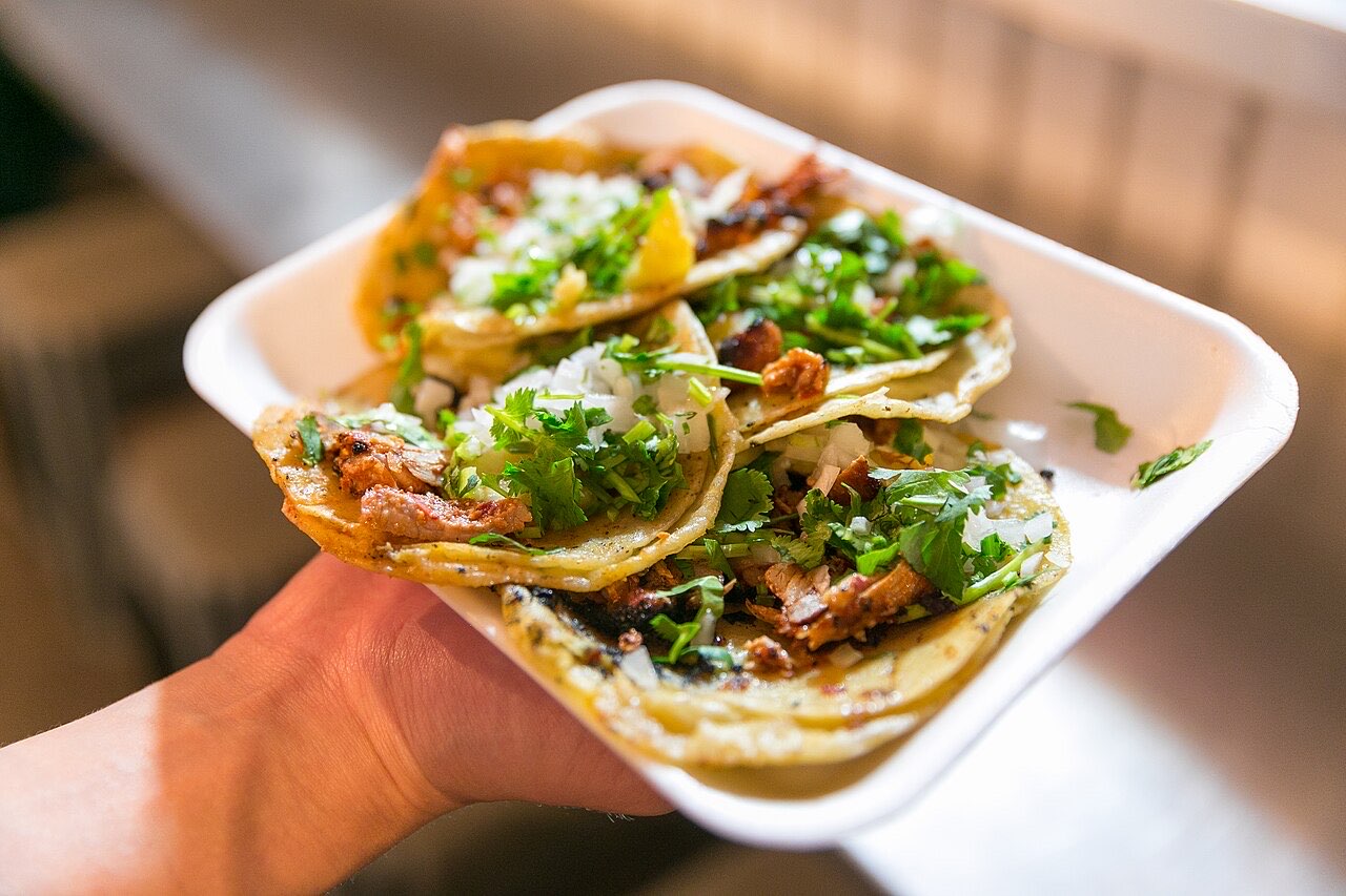 Three tacos al pastor with cilantro and onion